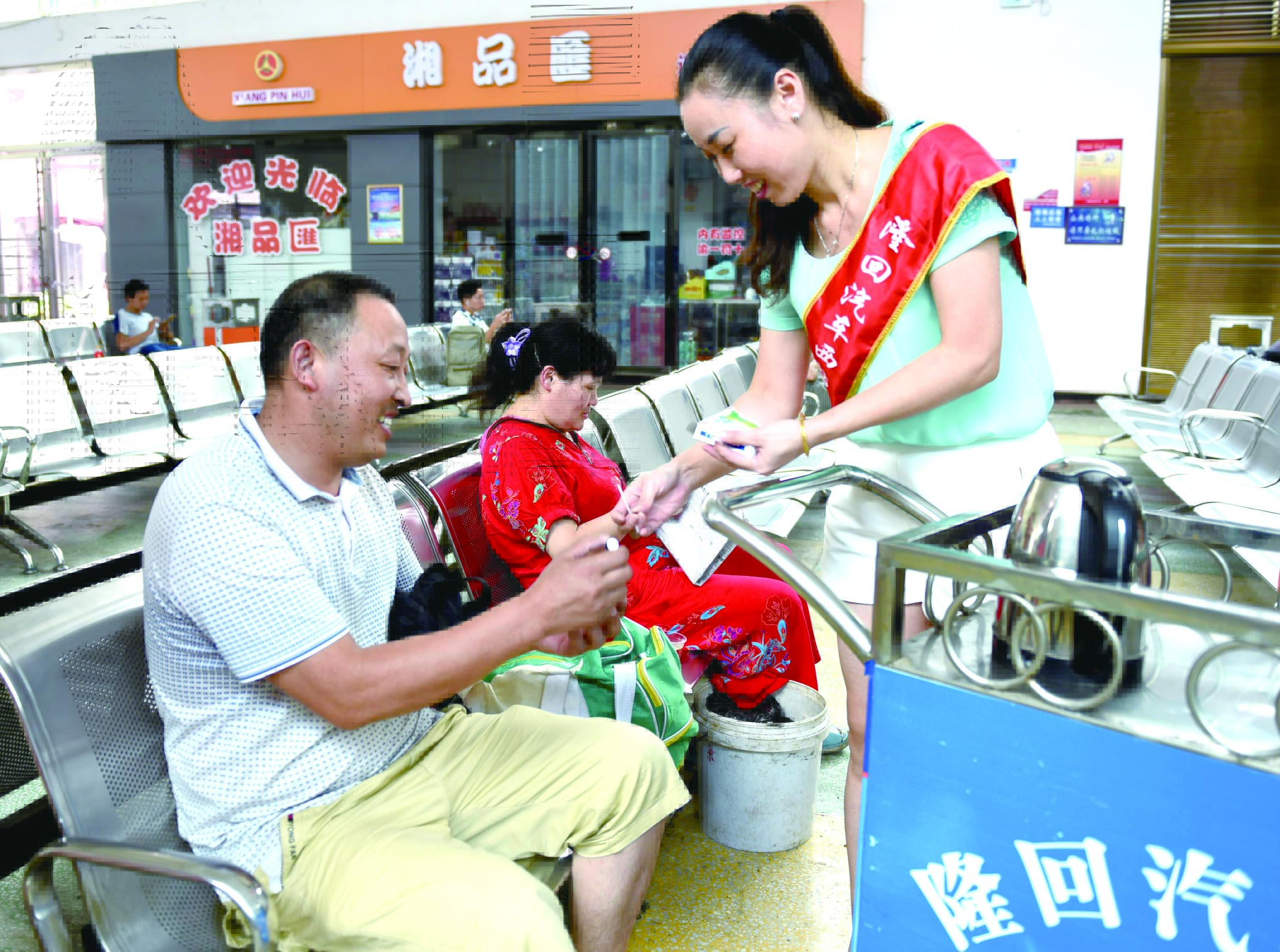 隆回分公司汽車西站工作人員正在為旅客免費(fèi)贈送藿香正氣水。